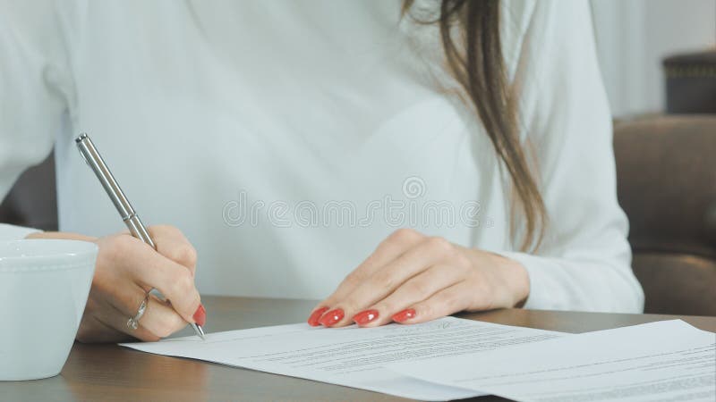 Mano de la mujer que pone la firma en contrato fotografía de archivo Mano de la mujer que pone la firma en contrato fotografía de archivo