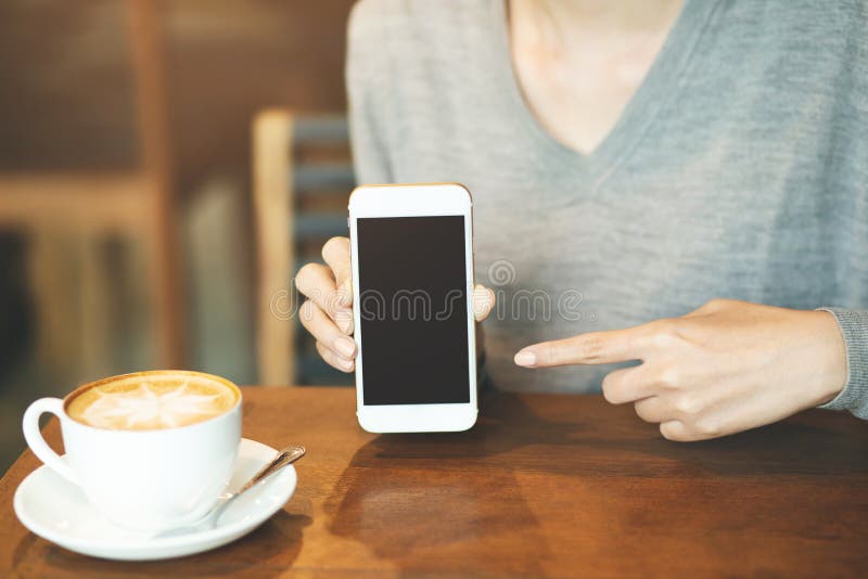 Mano de la mujer que sostiene el teléfono elegante móvil con la pantalla de escritorio en blanco imágenes de archivo libres de regalías Mano de la mujer que sostiene el teléfono elegante móvil con la pantalla de escritorio en blanco imágenes de archivo libres de regalías