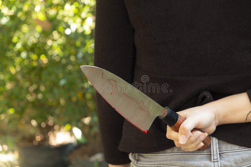 Mano de la mujer que sostiene un cuchillo sangriento en un fondo negro, concepto social de Halloween de la violencia, foto del as fotografía de archivo libre de regalías Mano de la mujer que sostiene un cuchillo sangriento en un fondo negro, concepto social de Halloween de la violencia, foto del as fotografía de archivo libre de regalías