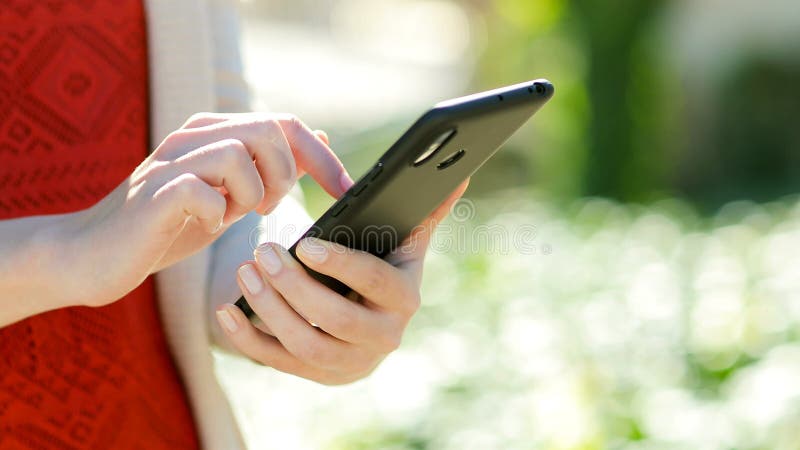 Mano de mujer usando teléfono móvil en un parque