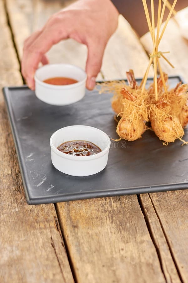 Mano del cuoco unico che mette salsa ai gamberetti croccanti fotografie stock Mano del cuoco unico che mette salsa ai gamberetti croccanti fotografie stock
