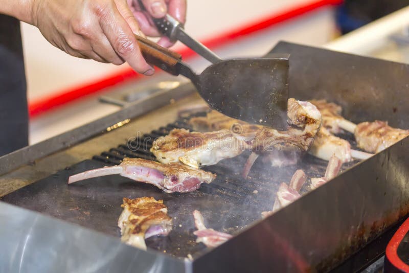 Mano del hombre que cocina la carne del hueso o el filete deliciosa de la barbacoa con Turner en la cacerola caliente fotografía de archivo Mano del hombre que cocina la carne del hueso o el filete deliciosa de la barbacoa con Turner en la cacerola caliente fotografía de archivo