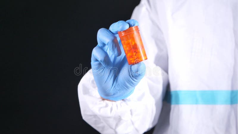 Mano del médico en guantes protectores sujetando el recipiente de la píldora con espacio de copia almacen de video