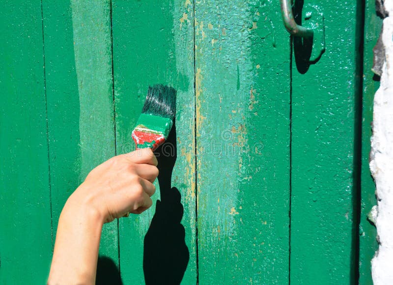 Mano del trabajador con el cepillo que pinta la puerta de madera vieja fotos de archivo libres de regalías Mano del trabajador con el cepillo que pinta la puerta de madera vieja fotos de archivo libres de regalías
