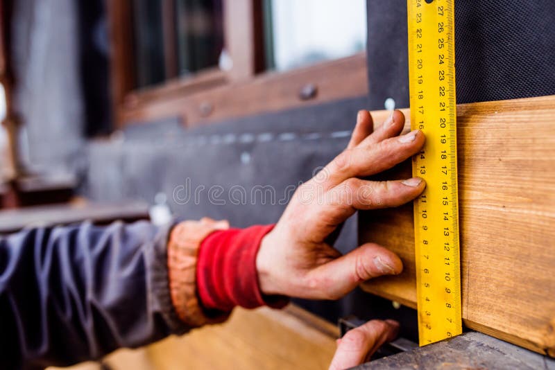 Mano del trabajador irreconocible, haciendo la fachada, BO de madera de medición fotografía de archivo libre de regalías Mano del trabajador irreconocible, haciendo la fachada, BO de madera de medición fotografía de archivo libre de regalías