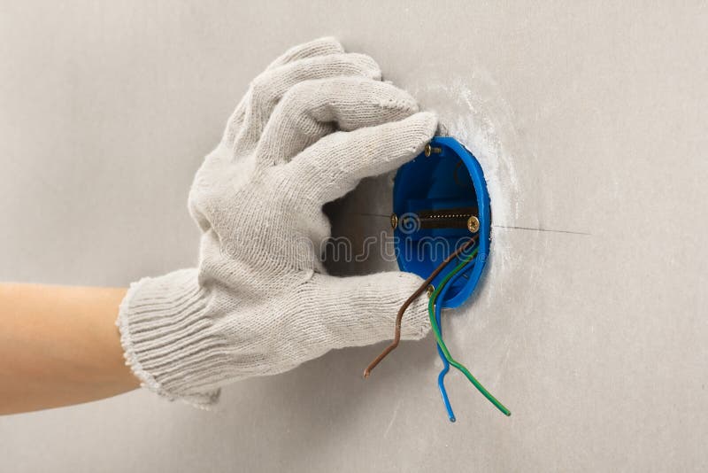 Mano dell'elettricista in guanto che installa scatola di distribuzione di plastica fotografia stock libera da diritti Mano dell'elettricista in guanto che installa scatola di distribuzione di plastica fotografia stock libera da diritti