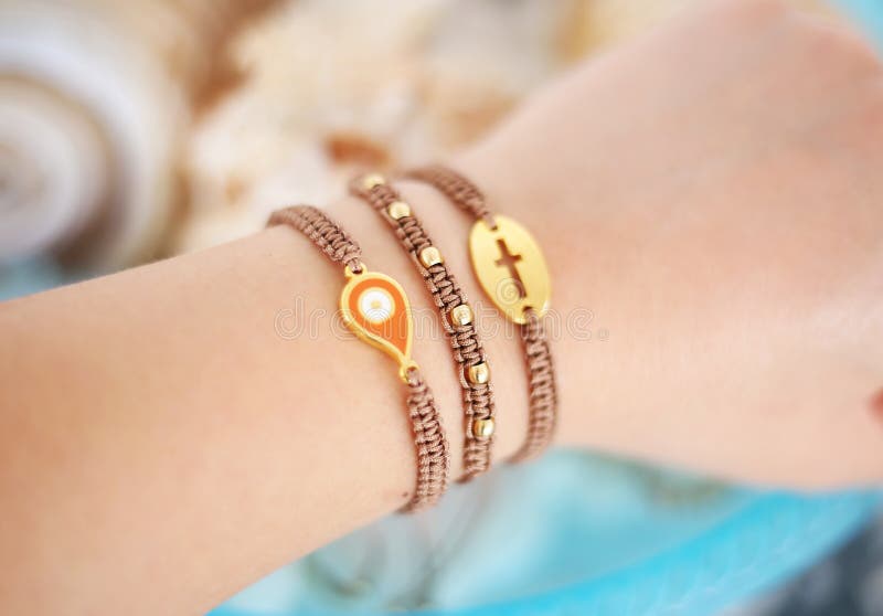 Mano della donna che indossa i braccialetti marroni alla moda con il malocchio ed i braccialetti inter- del macramè fotografia stock libera da diritti
