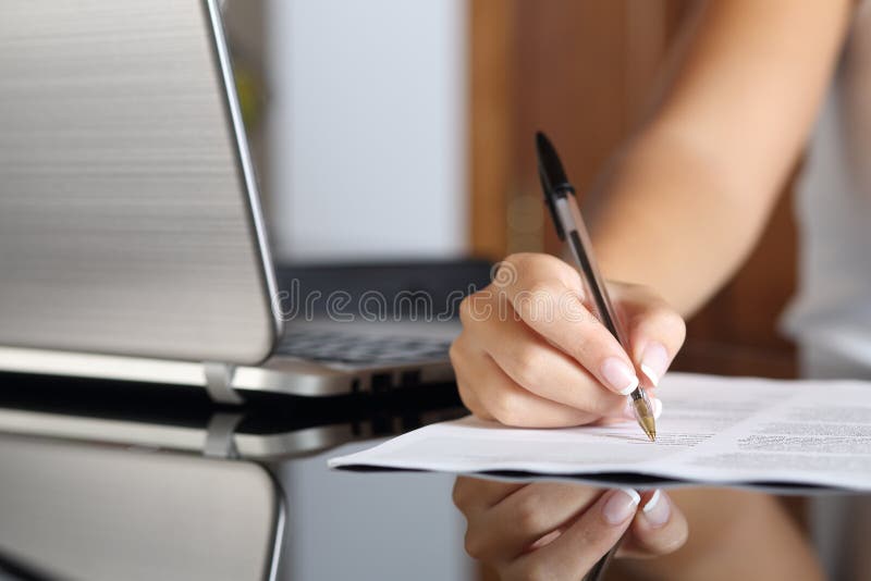 Mano della donna che scrive un contratto con un computer portatile accanto