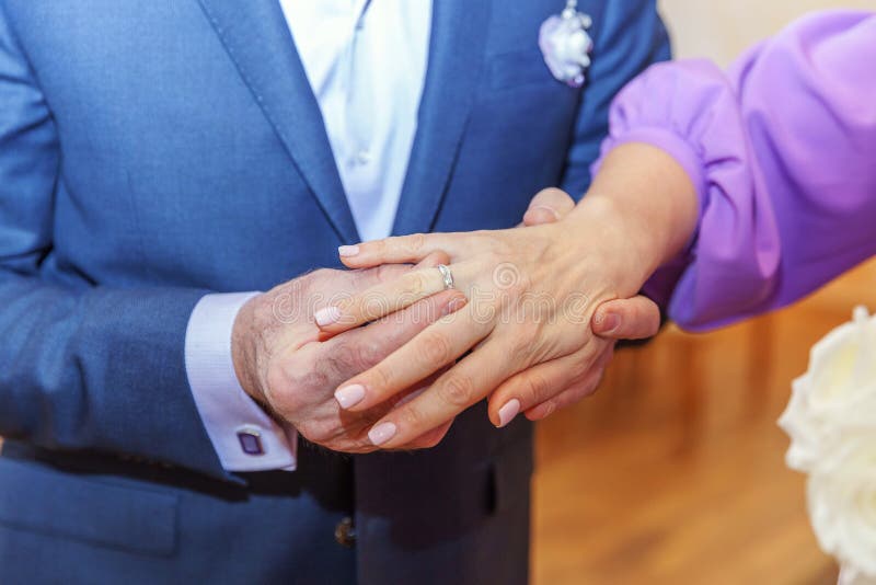 Mano dello sposo che mette fede nuziale sul dito della sposa fotografie stock Mano dello sposo che mette fede nuziale sul dito della sposa fotografie stock