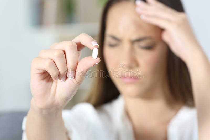 Mano enferma de la mujer que muestra una píldora del calmante imagen de archivo Mano enferma de la mujer que muestra una píldora del calmante imagen de archivo