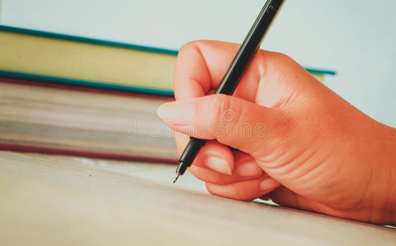 Mano femenina con la escritura de la camisa de la primavera algo con la pluma fotografía de archivo Mano femenina con la escritura de la camisa de la primavera algo con la pluma fotografía de archivo