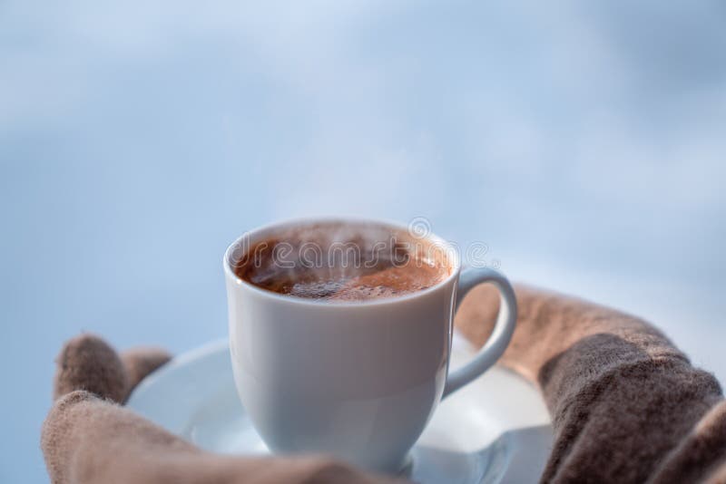 Mano femenina en las manoplas que sostienen la taza con café caliente Concepto del invierno fotografía de archivo Mano femenina en las manoplas que sostienen la taza con café caliente Concepto del invierno fotografía de archivo