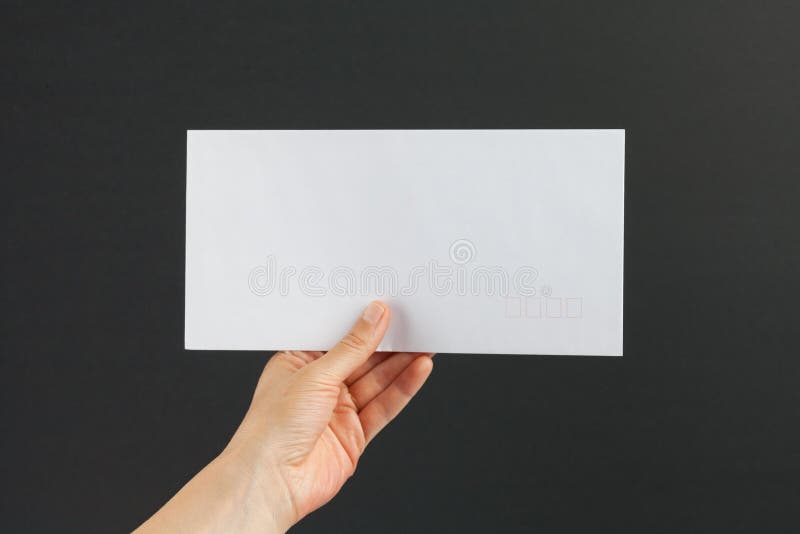 Mano femenina que entrega un sobre blanco en fondo negro fotos de archivo Mano femenina que entrega un sobre blanco en fondo negro fotos de archivo