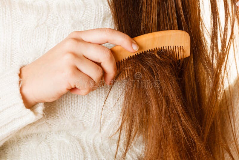 Female hand combing with brush her dry damaged long hair. Daily preparation for looking nice. Female hand combing with brush her dry damaged long hair. Daily preparation for looking nice.