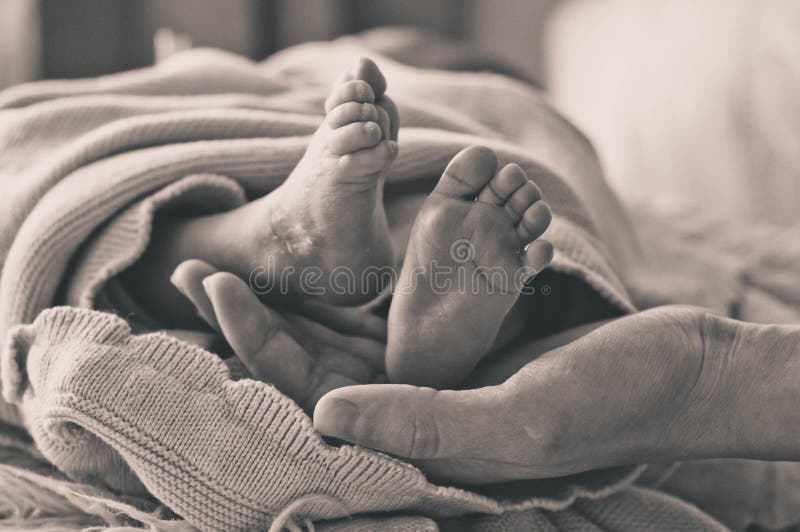 Mano femminile che tiene le sue gambe del neonato Mamma con il suo bambino Maternit?, famiglia, concetto di nascita fotografie stock Mano femminile che tiene le sue gambe del neonato Mamma con il suo bambino Maternit?, famiglia, concetto di nascita fotografie stock