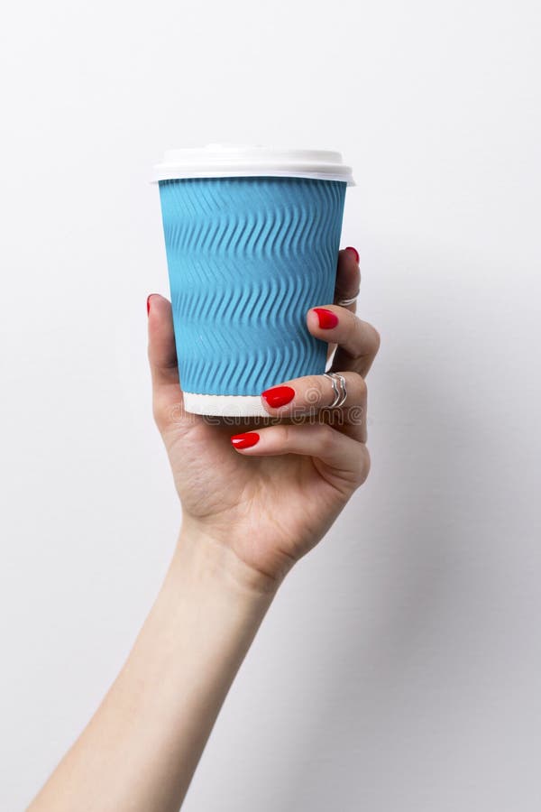 Mano femminile con il manicure rosso che tiene una tazza di carta del caff? su bianco fotografie stock Mano femminile con il manicure rosso che tiene una tazza di carta del caff? su bianco fotografie stock