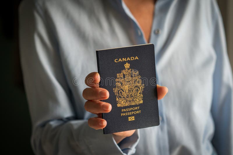 Mano femminile non riconoscibile con passaporto cittadino canadese. Donna anonima con maniche a maniche piene, camicetta, in piedi, che mostra il normale passaporto blu del cittadino, stampato con simboli color oro e parole Canada sulla copertina di copertina