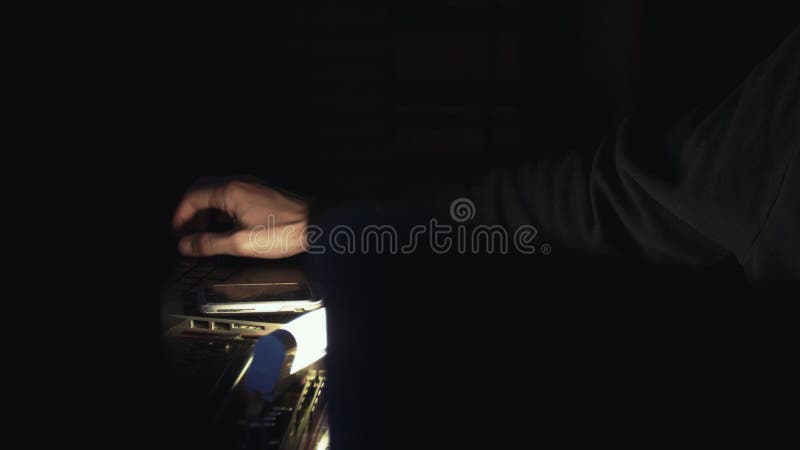 Mano maschio del pirata informatico nel codice di battitura a macchina della crepa del cappuccio facendo uso dei computer nella s
