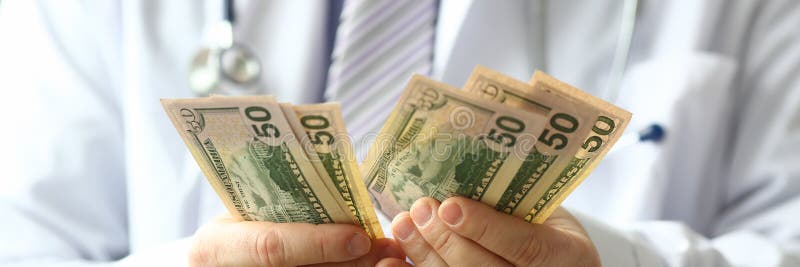 Mano masculina del efectivo del dólar del hald del doctor a disposición