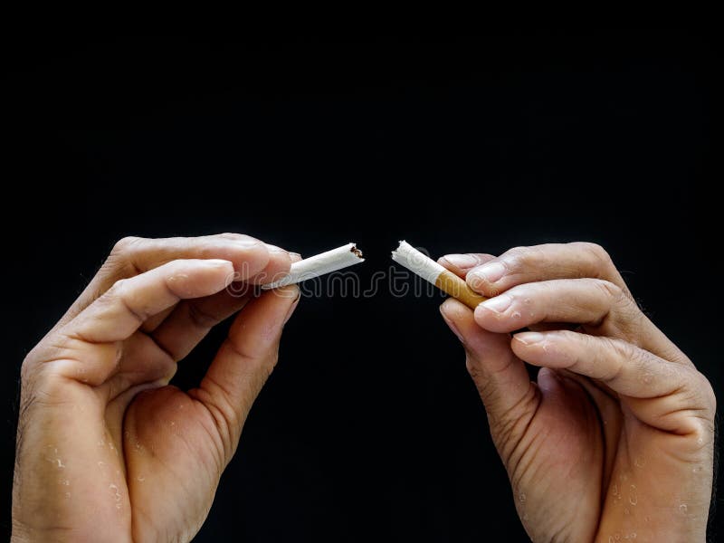 Mano masculina que machaca el cigarrillo en el fondo negro, concepto Quitti foto de archivo libre de regalías Mano masculina que machaca el cigarrillo en el fondo negro, concepto Quitti foto de archivo libre de regalías