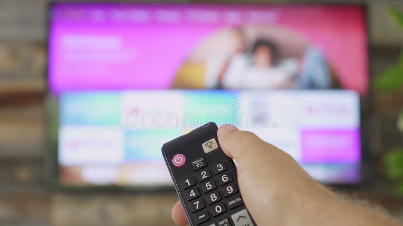 Mano masculina sujeta el mando a distancia de la tv y cambia los canales de tv