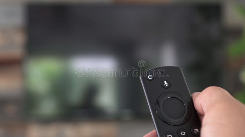 Mano masculina sujetando el mando a distancia de la tv y encendiendo la tv inteligente