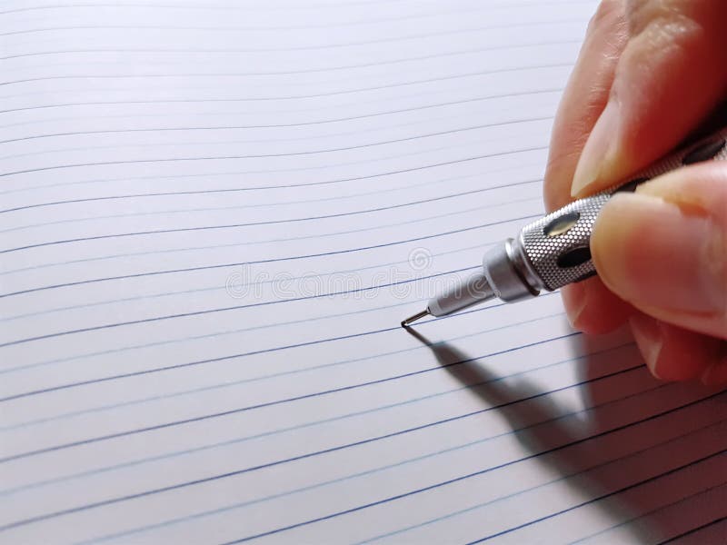 Mano que lleva a cabo notas mecánicas de la escritura del lápiz sobre el cuaderno foto de archivo Mano que lleva a cabo notas mecánicas de la escritura del lápiz sobre el cuaderno foto de archivo