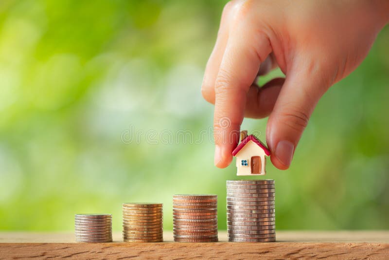 Mano que pone el modelo de la casa en pilas de la moneda foto de archivo libre de regalías Mano que pone el modelo de la casa en pilas de la moneda foto de archivo libre de regalías