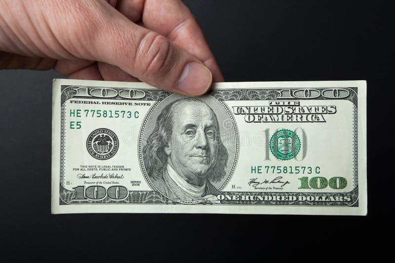 Mano y billete de dólar 100 en un fondo negro Primer imágenes de archivo libres de regalías Mano y billete de dólar 100 en un fondo negro Primer imágenes de archivo libres de regalías