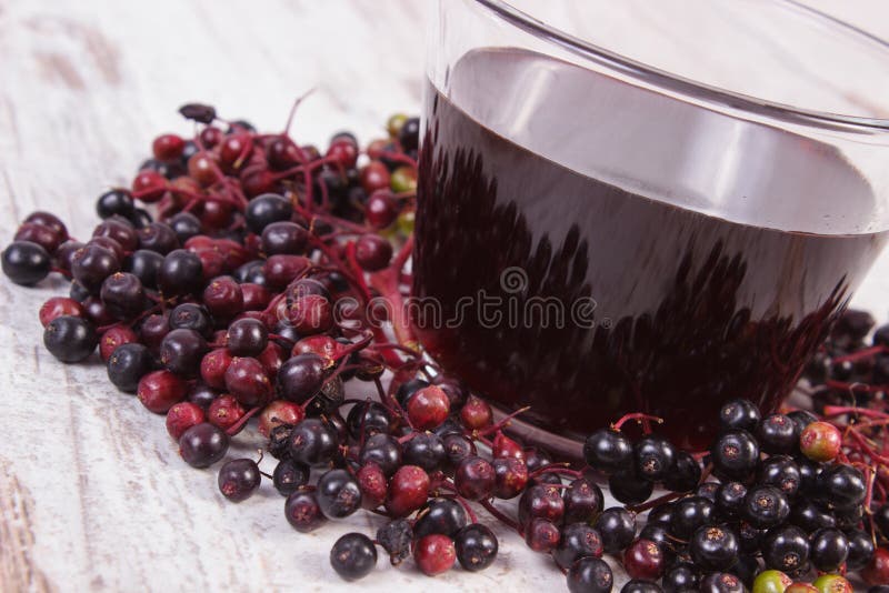 Manojo de baya del saúco fresca con el jugo en el viejo fondo de madera, nutrición sana foto de archivo libre de regalías Manojo de baya del saúco fresca con el jugo en el viejo fondo de madera, nutrición sana foto de archivo libre de regalías