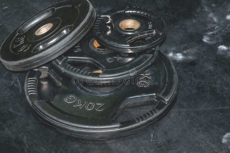 Manojo de placas negras pesadas del peso del barbell en el piso del gimnasio preparado para la imagen oscura del contraste fuerte imagen de archivo Manojo de placas negras pesadas del peso del barbell en el piso del gimnasio preparado para la imagen oscura del contraste fuerte imagen de archivo