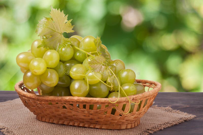 Manojo de uvas verdes maduras en una tabla de madera con el fondo borroso imagen de archivo