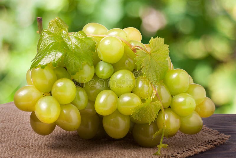 Manojo de uvas verdes maduras en una tabla de madera con el fondo borroso foto de archivo libre de regalías