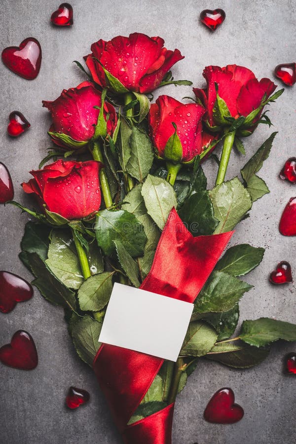 Manojo grande de las flores con las rosas rojas, la cinta, la tarjeta de papel en blanco y los corazones en fondo gris imagenes de archivo Manojo grande de las flores con las rosas rojas, la cinta, la tarjeta de papel en blanco y los corazones en fondo gris imagenes de archivo