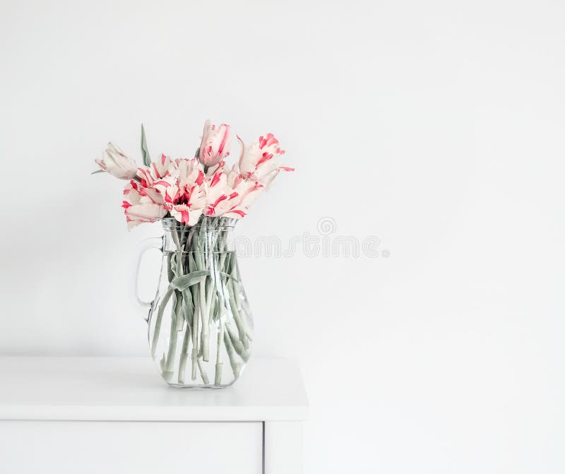 Manojo hermoso de tulipanes en el florero de cristal en la tabla blanca en la pared Flores en diseño interior fotografía de archivo libre de regalías Manojo hermoso de tulipanes en el florero de cristal en la tabla blanca en la pared Flores en diseño interior fotografía de archivo libre de regalías