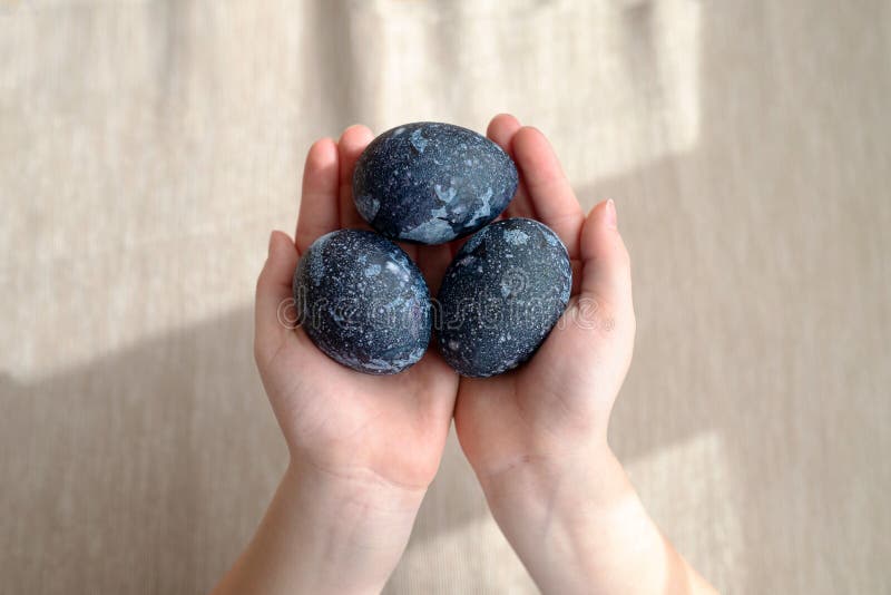 Manos con el azul oscuro cósmico con puntos blancos pintados huevos de Pascua. concepto de pascua feliz imágenes de archivo libres de regalías