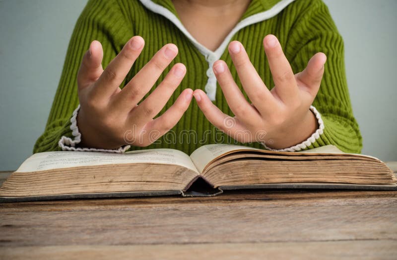 Manos con la biblia en la tabla de madera imagen de archivo libre de regalías Manos con la biblia en la tabla de madera imagen de archivo libre de regalías