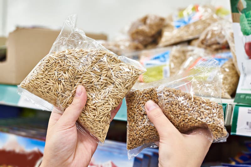 Manos con las semillas de la avena para la comida en tienda imagen de archivo Manos con las semillas de la avena para la comida en tienda imagen de archivo