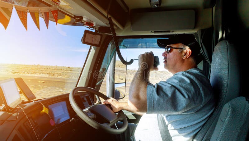 Manos correctas del tráfico del camión grande de los conductores de camión que sostienen el volante de radio y foto de archivo libre de regalías Manos correctas del tráfico del camión grande de los conductores de camión que sostienen el volante de radio y foto de archivo libre de regalías