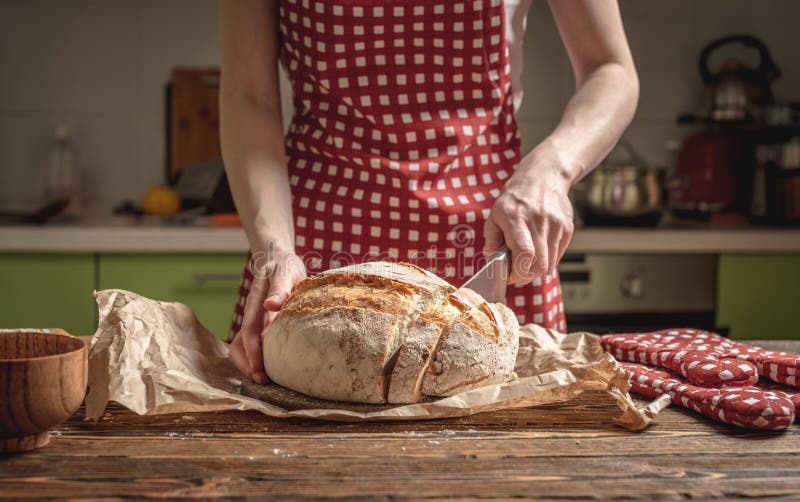 Manos cortadas con un cuchillo pan fresco natural casero con una corteza dorada sobre fondo de madera. productos de panadería foto de archivo libre de regalías