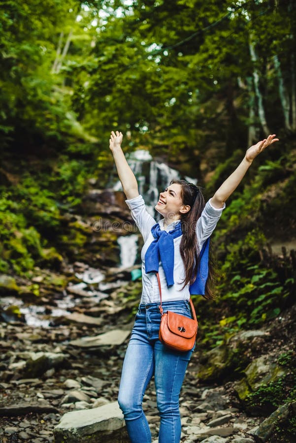 Manos de extensión felices de la mujer joven que disfrutan de la naturaleza con la cascada en fondo imágenes de archivo libres de regalías Manos de extensión felices de la mujer joven que disfrutan de la naturaleza con la cascada en fondo imágenes de archivo libres de regalías