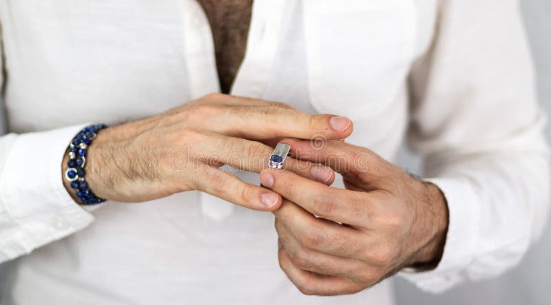 Manos De Hombres Blancos Que Ponen Un Anillo De Plata Con Un Zafiro Azul. Joyería Hombres. De Compromiso Imagen de archivo - Imagen de ajuste, elegancia: 194307075