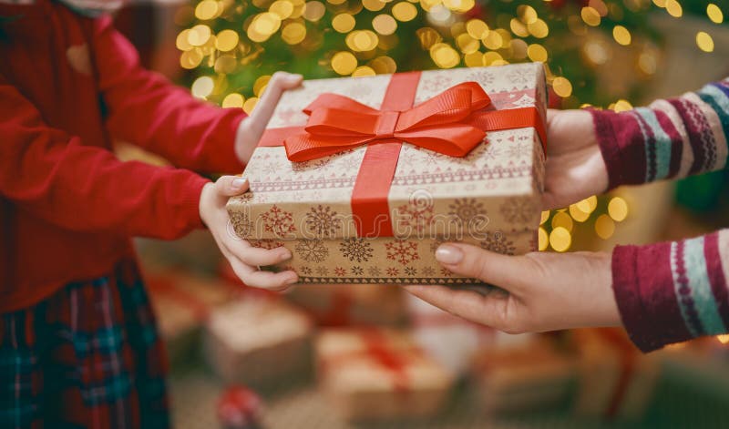 Manos de los padres dándole un regalo de Navidad a los hijos