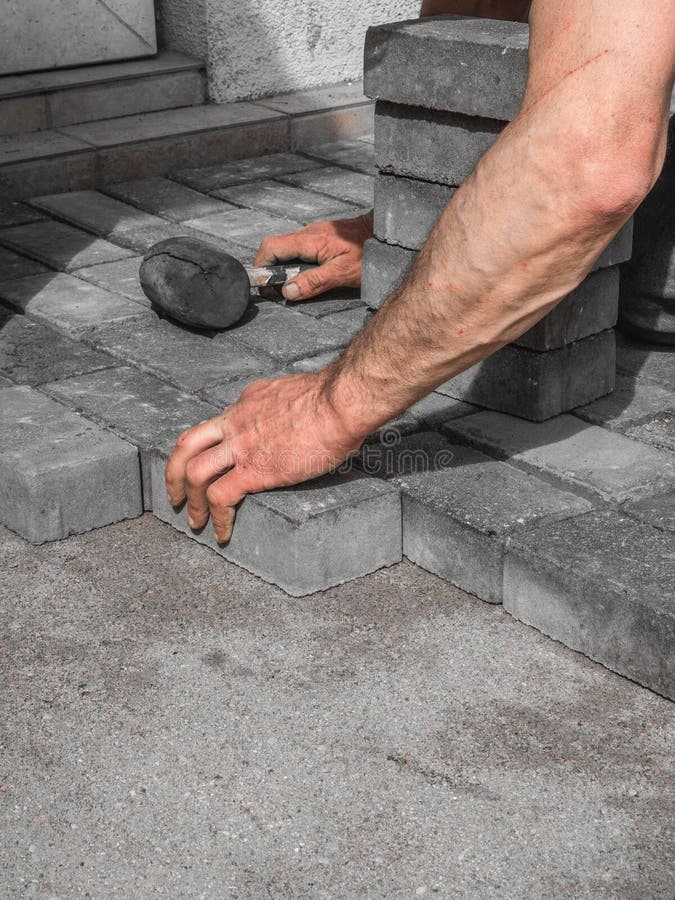 Manos de un trabajador manual que pone bloques de pavimentaci?n concretos imágenes de archivo libres de regalías Manos de un trabajador manual que pone bloques de pavimentaci?n concretos imágenes de archivo libres de regalías