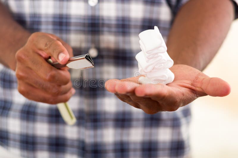 Manos del primer del hombre con afeitar la pila de la espuma en la mano izquierda, shavette en otro, camisa cuadrada azul blanca fotografía de archivo libre de regalías Manos del primer del hombre con afeitar la pila de la espuma en la mano izquierda, shavette en otro, camisa cuadrada azul blanca fotografía de archivo libre de regalías