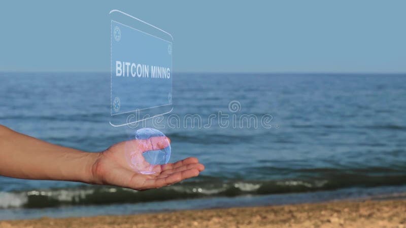 Manos en la explotación minera de Bitcoin del texto del holograma del control de la playa