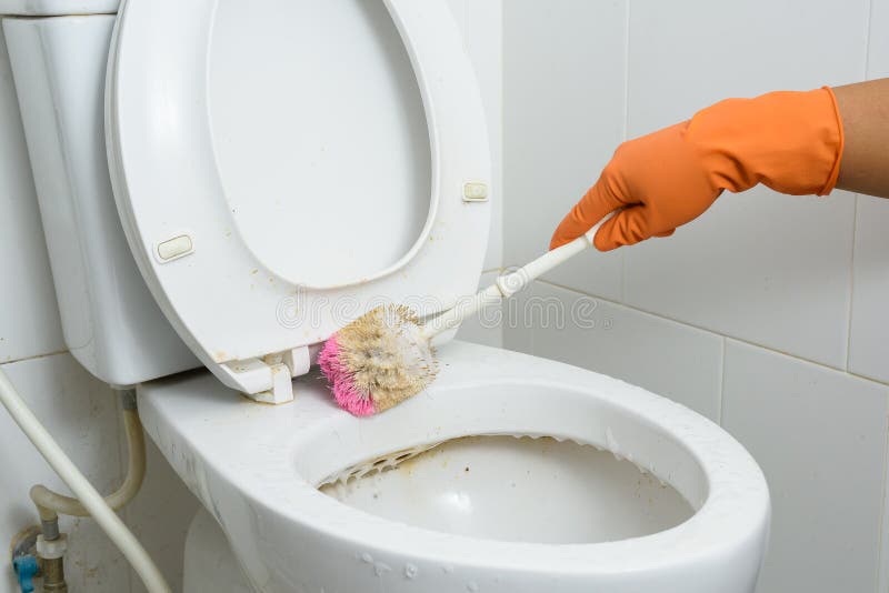 Manos en los guantes anaranjados que limpian WC, retrete, servicio usando cepillo imágenes de archivo libres de regalías Manos en los guantes anaranjados que limpian WC, retrete, servicio usando cepillo imágenes de archivo libres de regalías