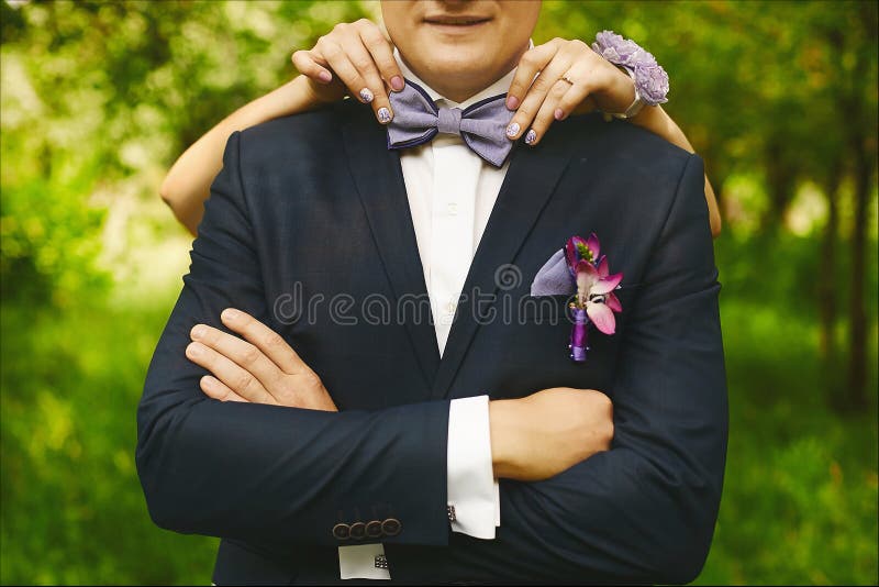 Manos femeninas con la manicura de moda que ajusta el bowtie de moda en el cuello de un hombre hermoso joven en un traje que se c fotografía de archivo libre de regalías Manos femeninas con la manicura de moda que ajusta el bowtie de moda en el cuello de un hombre hermoso joven en un traje que se c fotografía de archivo libre de regalías