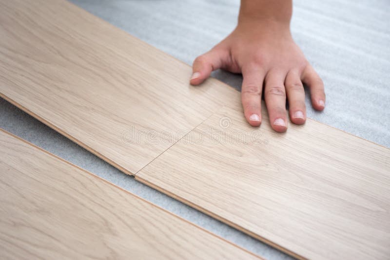 Manos masculinas que instalan el suelo de madera imagen de archivo Manos masculinas que instalan el suelo de madera imagen de archivo