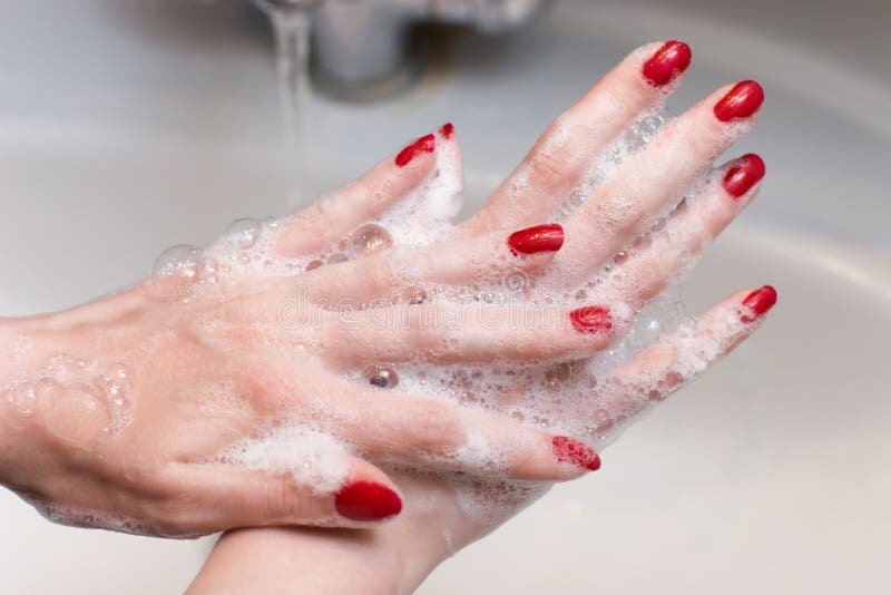 Washing hands with red nails. Scene in a bathroom. Washing hands with red nails. Scene in a bathroom.